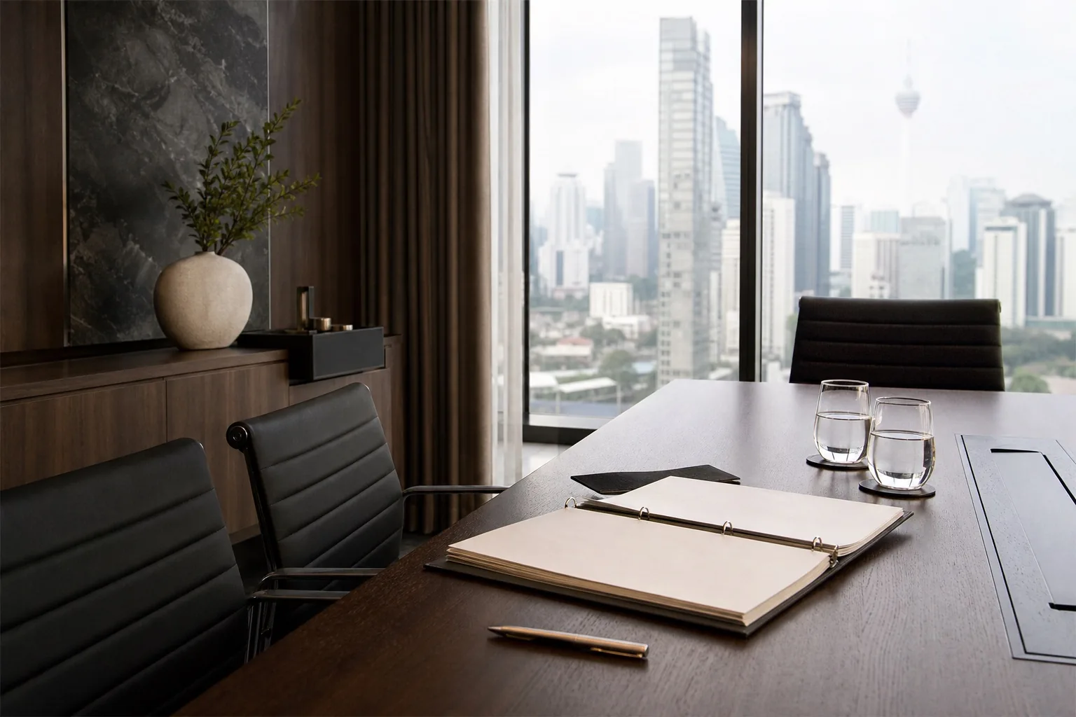An empty boardroom prepared with a financial binder and water glasses.